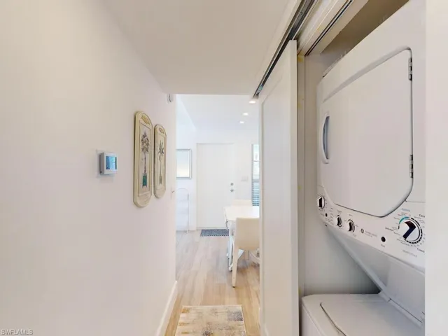 Laundry room with stacked washer and dryer and light wood-type flooring