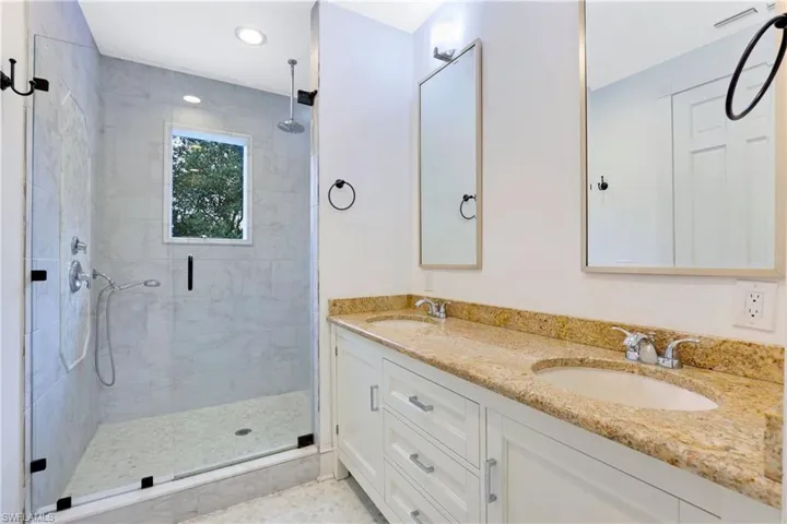 Full bathroom featuring a stall shower, double vanity, and recessed lighting