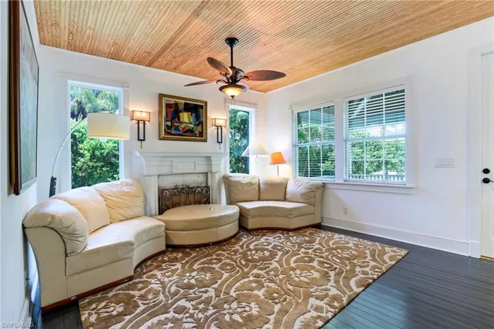 Living area featuring hardwood / wood-style flooring, wood ceiling, a fireplace, and a ceiling fan