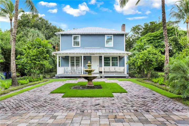 American foursquare style home with a porch, a metal roof, and a chimney