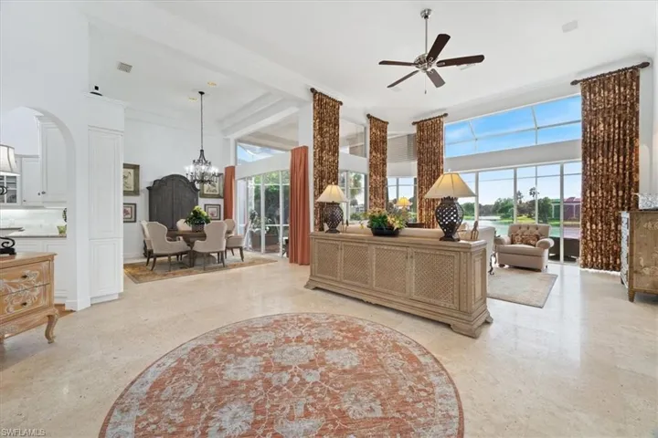 Living area featuring a towering ceiling, crown molding, a ceiling fan, and a chandelier