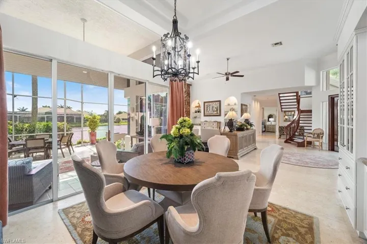 Dining room with a ceiling fan, a chandelier, a water view, and beamed ceiling