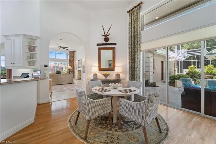 Dining area featuring a ceiling fan, a towering ceiling, light wood-style floors, arched walkways, and ornamental molding