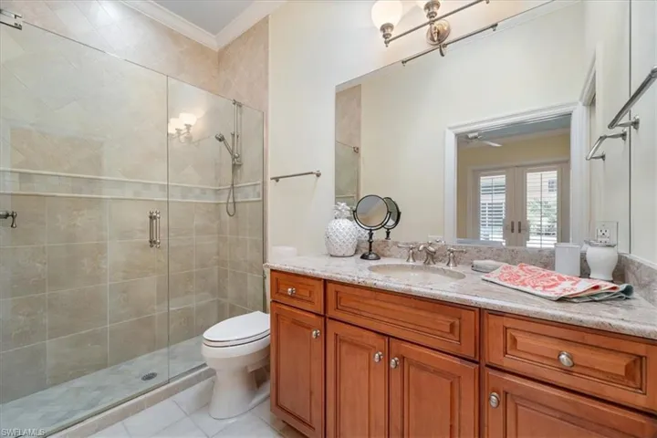 Full bathroom featuring ornamental molding, vanity, a stall shower, light tile patterned flooring, and french doors