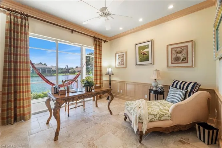 Home office with wainscoting, a water view, ornamental molding, a decorative wall, and a ceiling fan