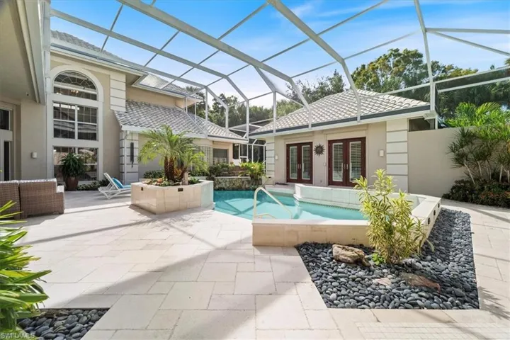 Swimming pool featuring glass enclosure, a patio area, french doors, and a sunroom