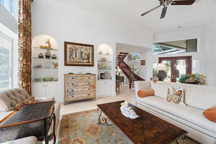 Living area featuring ornamental molding, plenty of natural light, built in shelves, stairs, and ceiling fan