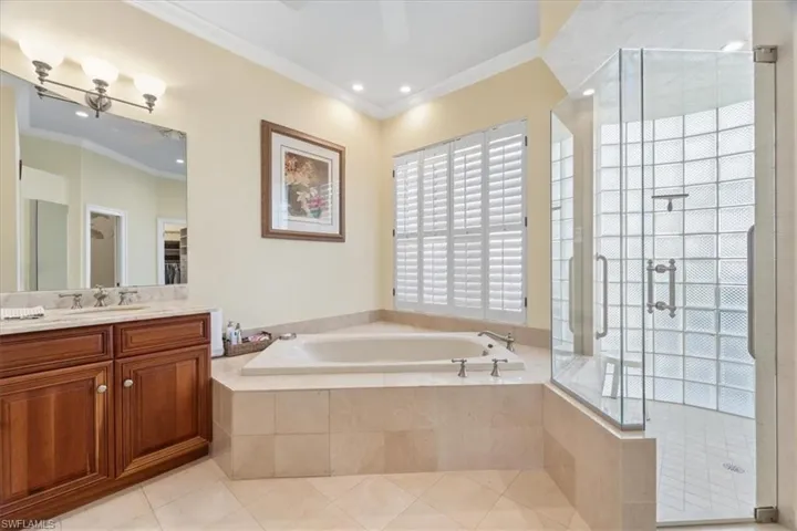 Full bathroom with vanity, a bath, ornamental molding, a shower stall, and light tile patterned floors