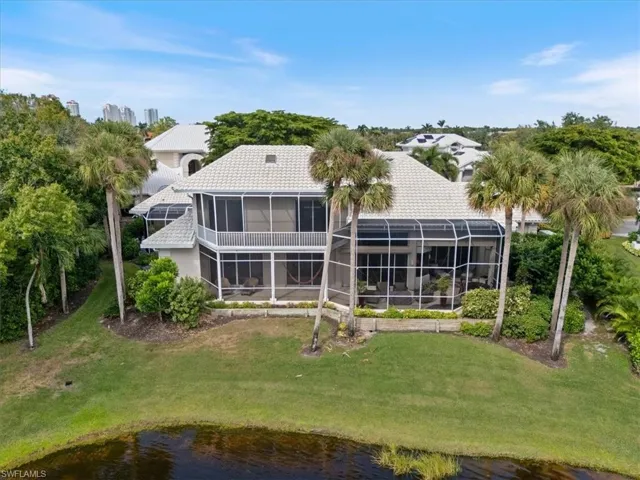 Back of property with a sunroom, a water view, a lanai, and a lawn
