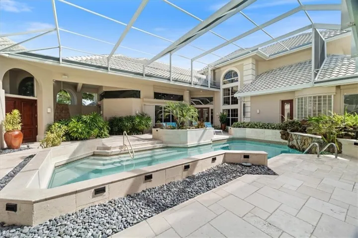 Swimming pool featuring a lanai, a sunroom, a patio area, and a hot tub