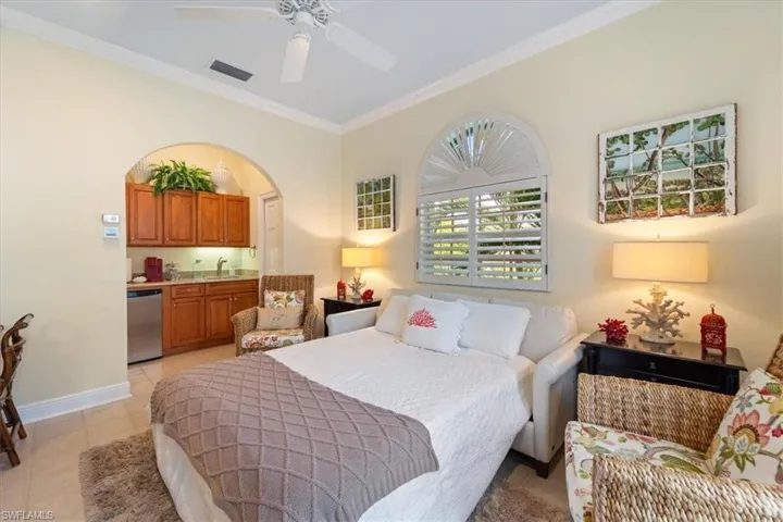 Bedroom with crown molding, light tile patterned flooring, and a ceiling fan