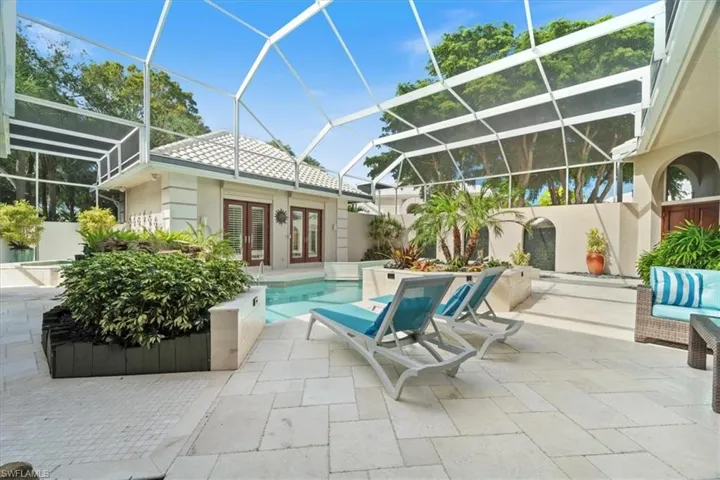 Outdoor pool featuring glass enclosure, a patio area, a sunroom, and french doors