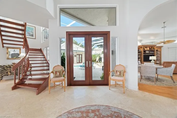 Entryway with french doors, arched walkways, stairway, and a high ceiling