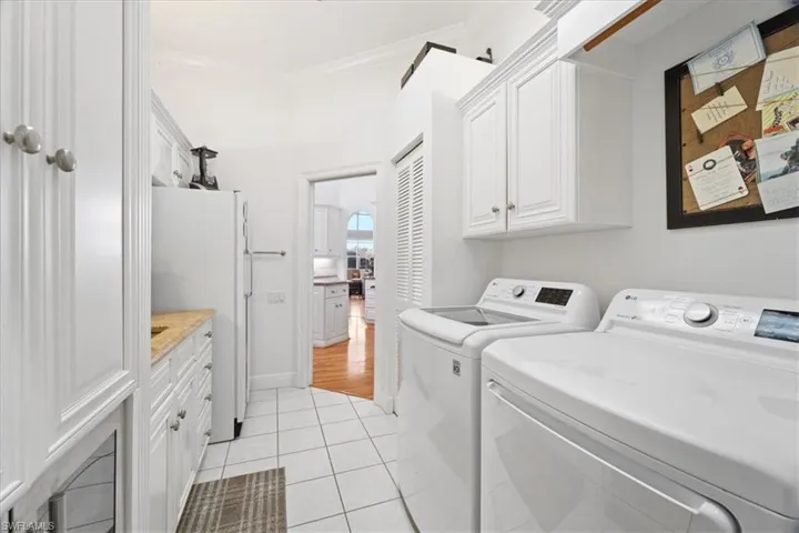 Laundry room featuring cabinet space, washing machine and dryer, light tile patterned floors, and crown molding