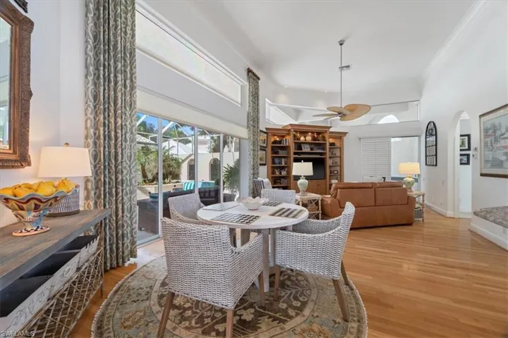 Dining room featuring ornamental molding, a high ceiling, plenty of natural light, arched walkways, and light wood finished floors