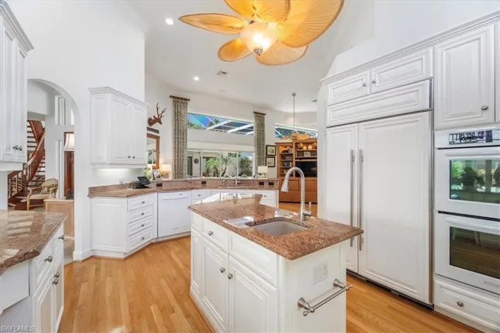 Kitchen with white appliances, light wood finished floors, recessed lighting, white cabinets, and light stone counters