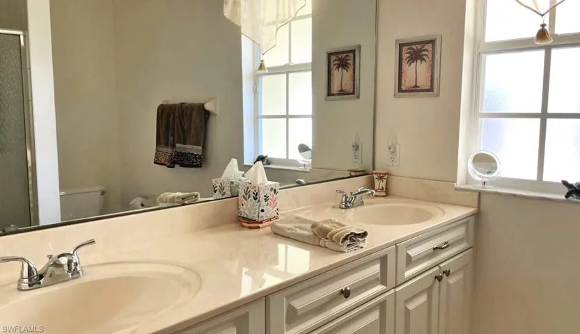 Bathroom featuring dual vanity, a wealth of natural light, and toilet