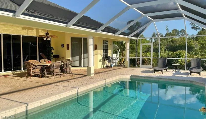 View of pool featuring a patio, glass enclosure, and ceiling fan