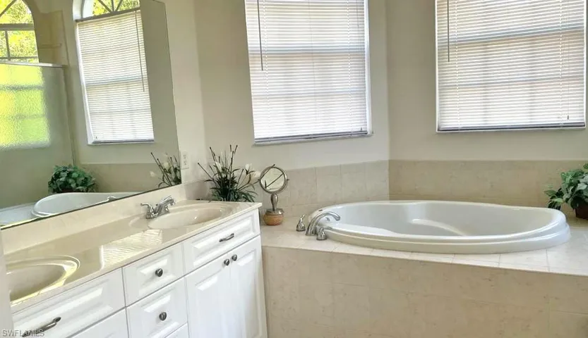 Bathroom featuring tiled bath, oversized vanity, and dual sinks