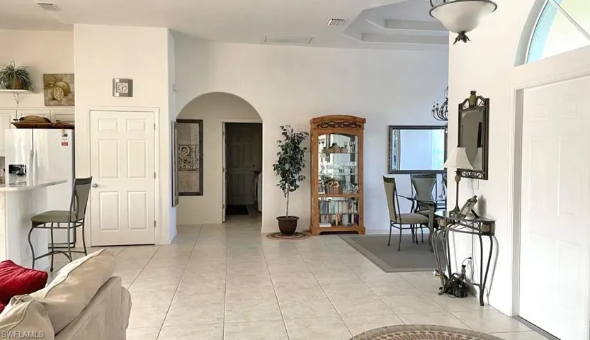 Tiled entryway with a high ceiling, a tray ceiling, and a healthy amount of sunlight