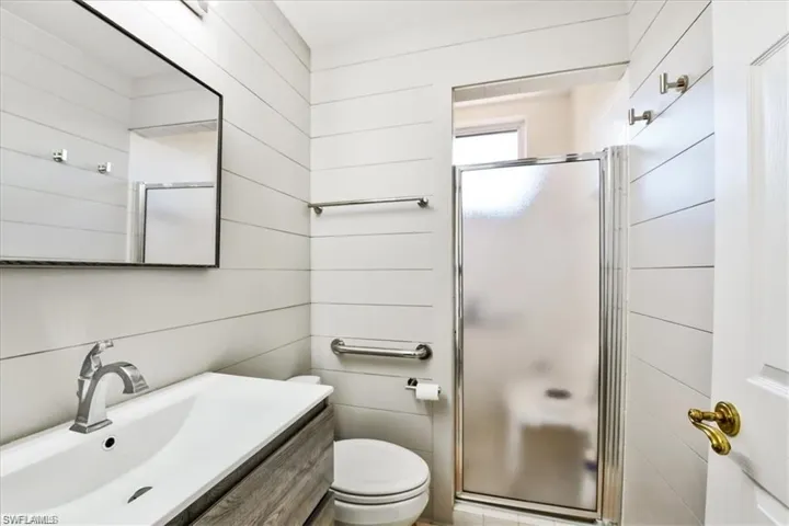 Bathroom featuring a shower with shower door, vanity, and toilet