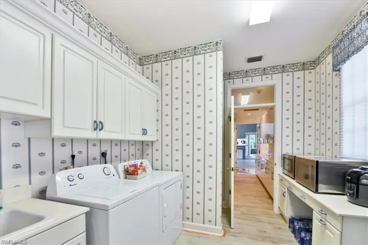 Laundry area with cabinets, a wealth of natural light, light wood-type flooring, independent washer and dryer, and sink