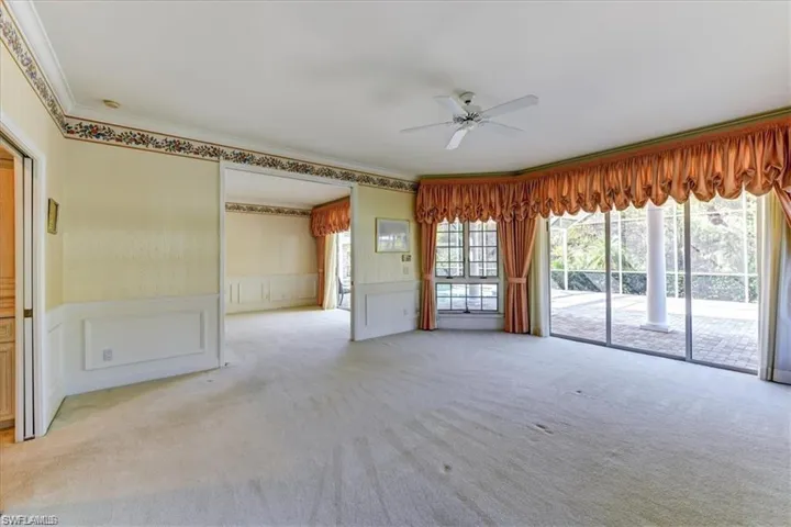 Carpeted spare room with crown molding and ceiling fan