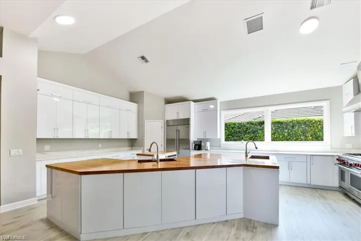 Kitchen with premium appliances, a center island with sink, light hardwood / wood-style flooring, and white cabinets
