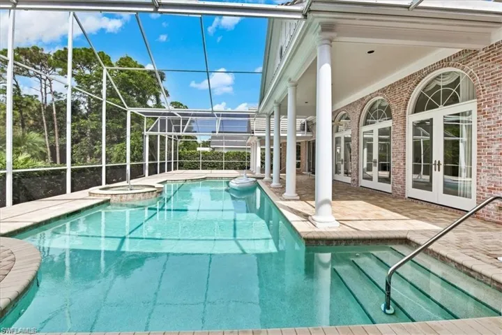 View of swimming pool featuring a lanai, an in ground hot tub, a patio area, and french doors