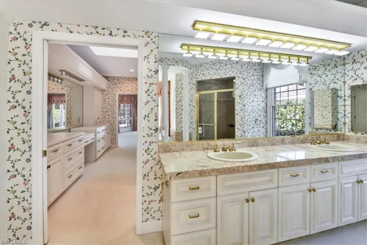 Bathroom featuring a wealth of natural light, an enclosed shower, oversized vanity, and dual sinks