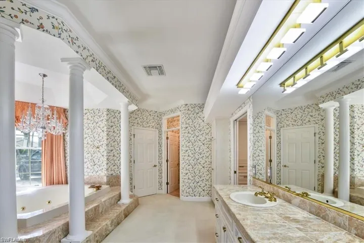 Bathroom featuring a chandelier, tile flooring, ornamental molding, vanity, and decorative columns