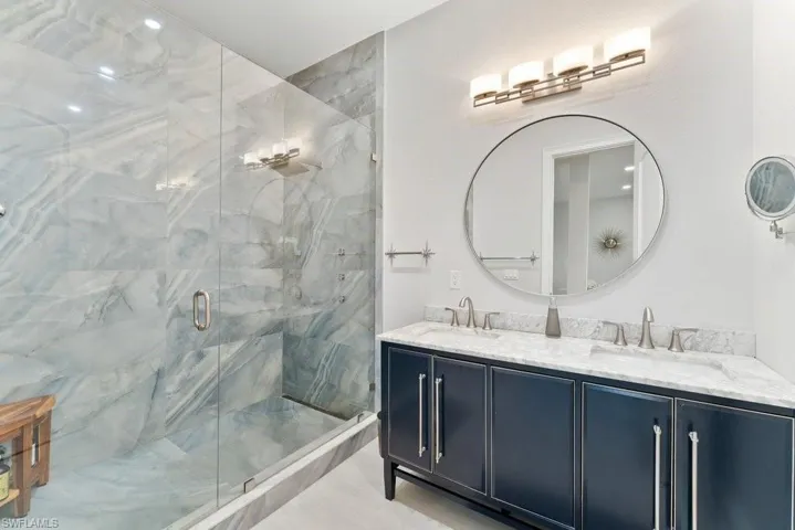 Full bathroom featuring double vanity and a marble finish shower