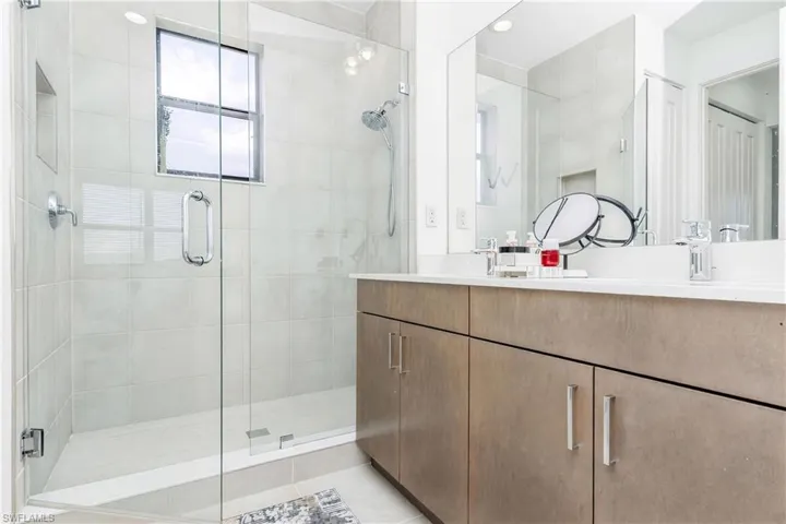 Glass-enclosed shower with tile surround and window