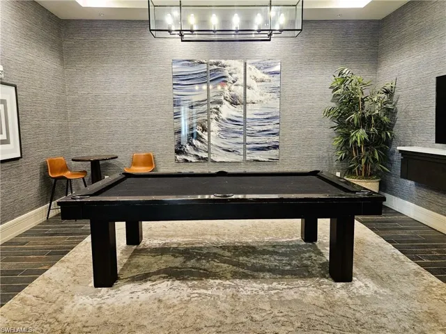 Textured wall covering, linear chandelier, dark wood-finish flooring, built-in floating cabinet, and recessed ceiling lighting