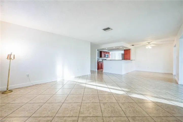 Unfurnished living room with ceiling fan and light tile patterned floors