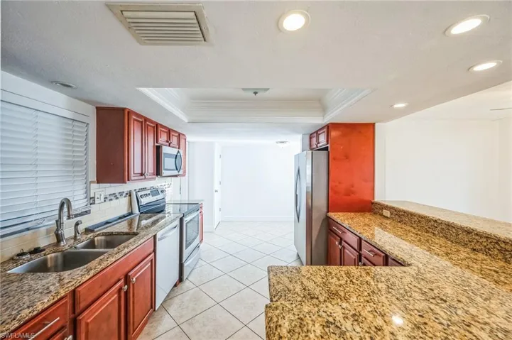 Kitchen with sink, a tray ceiling, ornamental molding, and appliances with stainless steel finishes