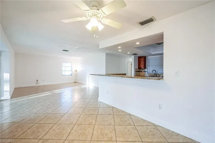 Unfurnished room featuring ceiling fan, a raised ceiling, sink, light tile patterned floors, and ornamental molding