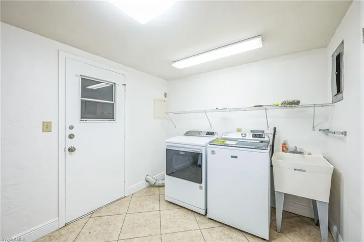 Clothes washing area with light tile patterned floors and washer and dryer