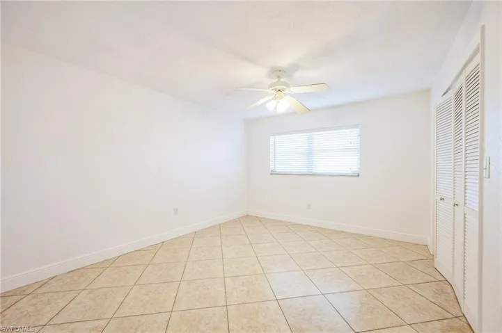 Unfurnished bedroom featuring ceiling fan, light tile patterned floors, and a closet