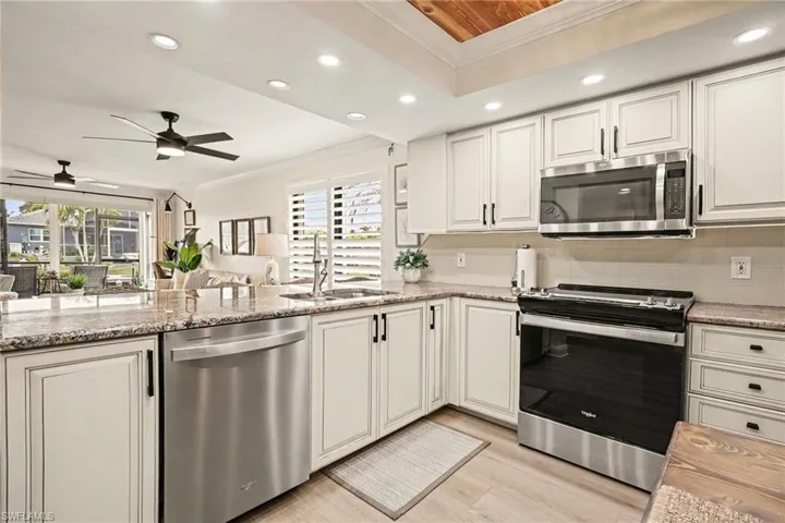 Kitchen with ornamental molding, stainless steel appliances, recessed lighting, open floor plan, and light stone countertops