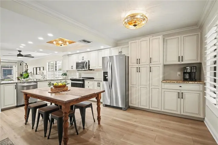 Kitchen with ornamental molding, stainless steel appliances, light wood-style flooring, recessed lighting, and light stone countertops