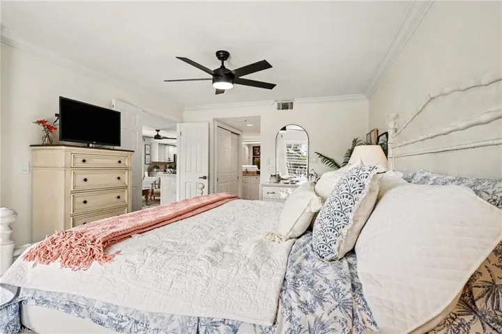 Bedroom featuring ornamental molding, connected bathroom, a ceiling fan, and a closet