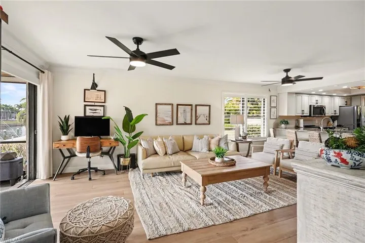 Living area with a ceiling fan, light wood-type flooring, and crown molding