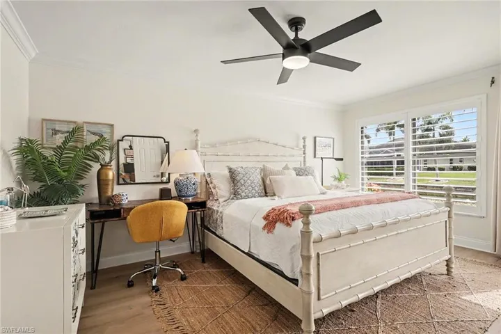 Bedroom with crown molding, light wood-style floors, and ceiling fan