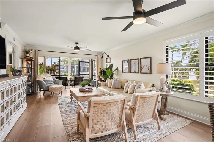 Living area featuring ornamental molding, light wood-type flooring, and ceiling fan