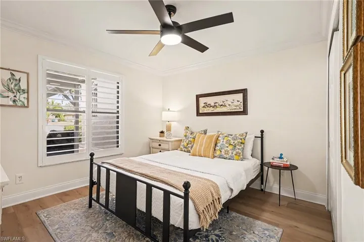 Bedroom featuring wood finished floors, crown molding, and ceiling fan