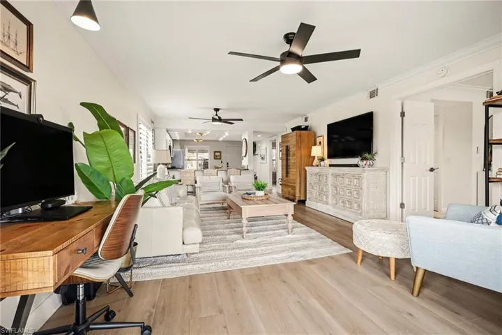 Living room with crown molding, light wood-type flooring, an office area, and a ceiling fan