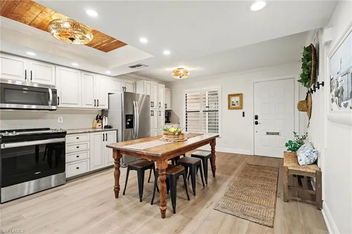 Dining space featuring crown molding, light wood-style flooring, recessed lighting, and a wooden tray ceiling