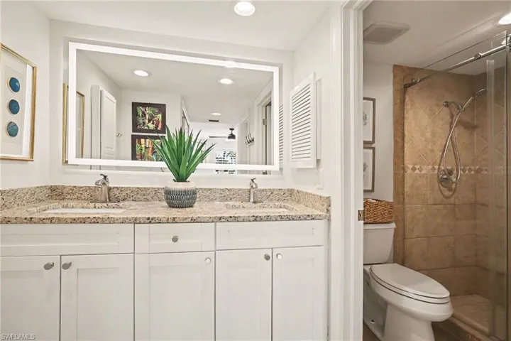 Full bathroom featuring a shower stall, double vanity, and recessed lighting
