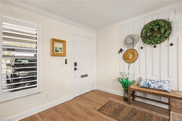 Foyer entrance featuring wood finished floors and crown molding
